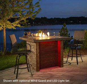 Two outdoor bar stool chairs with padded fabric, patio fire pit table at night with pond in background