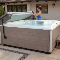 Person lifting cover off of hot tub with help from CoverCradle II Cover Lifter