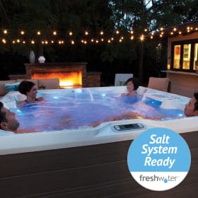People in Highlife collection hot tub model at nighttime with string lights overhead