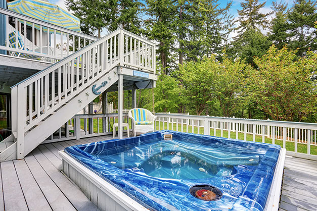 Hot tub on the first floor of a multilayered deck in a beautiful backyard