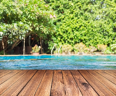 above ground pool with a deck in a beautifully landscaped backyard