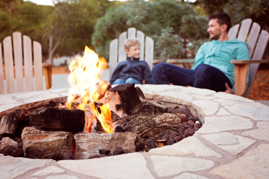 Siblings talking while sitting around fire pit