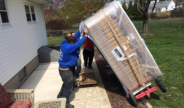 Crew Unloading A New Hot Tub Off A Hand Truck Onto A Patio