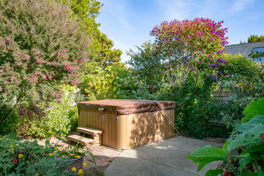 A closed hot tub with small steps in a garden during the day.