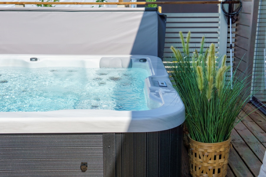 Hot tub sitting in enclosed backyard with rustic plant next to it