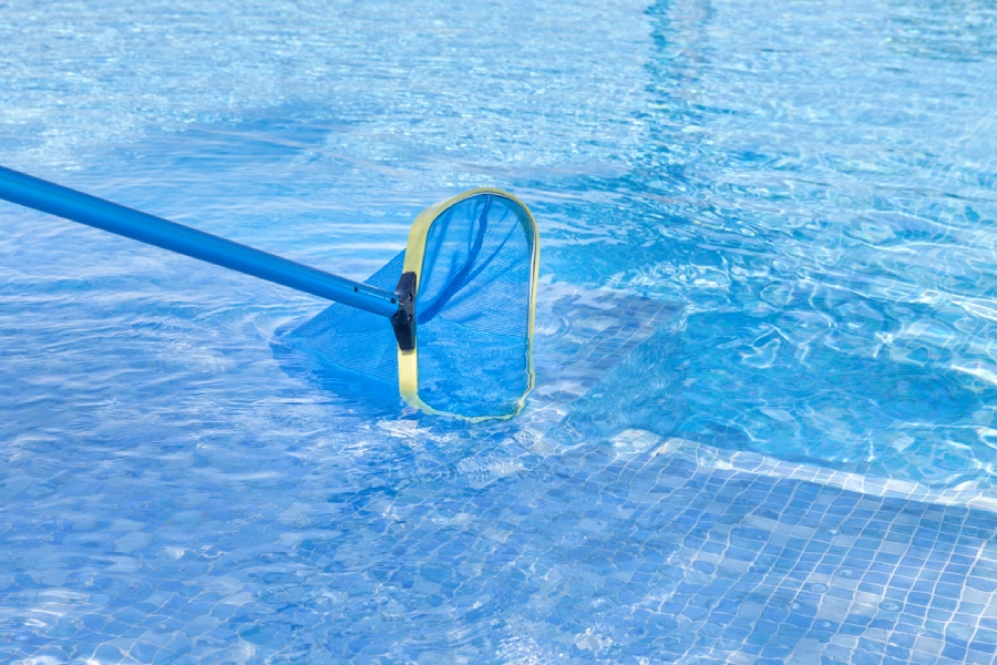 Inground swimming pool being cleaned with skimmer tool